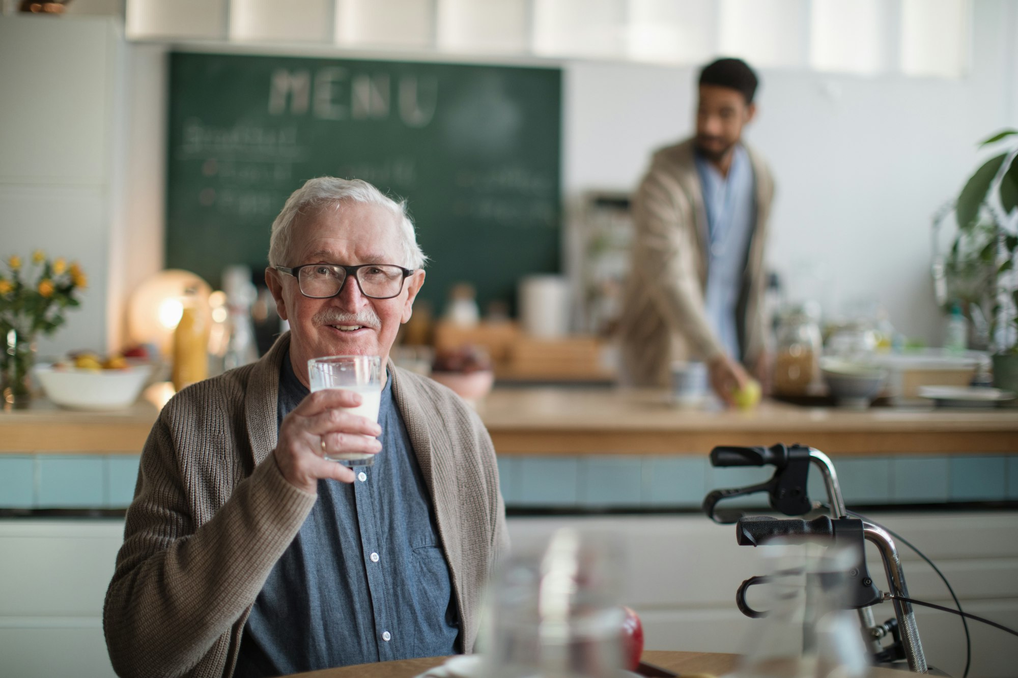 Smiling elderly man enjoying breakfast in nursing home care center